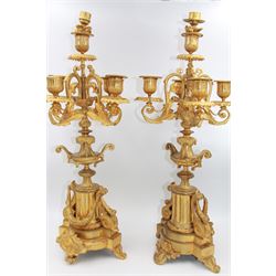 Pair of French Louis XV style gilt metal candelabra, each with four foliate scroll arms supporting fluted urn sockets above foliate edged drop pans, and surrounding a central conforming socket with foliate snuffers, upon ornately modelled stems with urn knops leading to fluted pedestals hung with husk swags, upon stepped bases with scroll feet, overall H53cm
