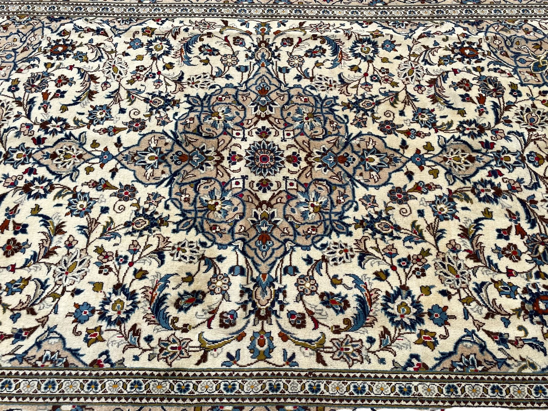 Persian Kashan ivory ground rug, central floral medallion surrounded by interlacing leafy branches and stylised plant motifs, scrolling spandrels, the border decorated with trailing branch and repeating palmettes, within floral pattern guard stripes 