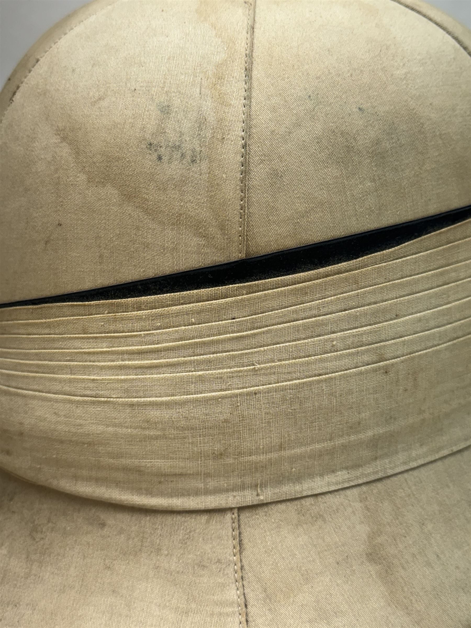 WWII Royal Navy officers sun helmet with large folded pagri and black top line, interior with green cloth covering to the peaks and original leather sweatband, with makers label 'Gieves Ltd London', with its original storage tin with indistinct painted lettering to the front 